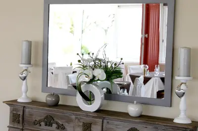 a mirror on a dresser with a vase of flowers at Logis Hôtel - Auberge du Pastel - Hôtel 3 étoiles et Restaurant in Nailloux