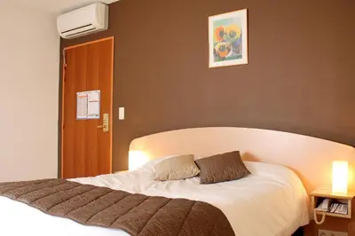 a bedroom with a large bed with white sheets at Logis Hôtel - Auberge du Pastel - Hôtel 3 étoiles et Restaurant in Nailloux