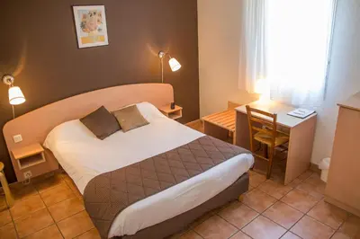 a hotel room with a bed and a desk at Logis Hôtel - Auberge du Pastel - Hôtel 3 étoiles et Restaurant in Nailloux