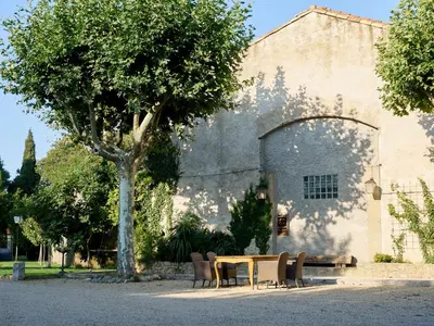 a table and chairs in front of a building with a tree at Domaine Des Agnelles in Villedaigne