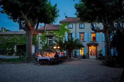 a group of people sitting at tables in front of a house at Domaine Des Agnelles in Villedaigne