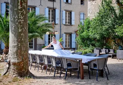 a woman standing at a table in front of a building at Domaine Des Agnelles in Villedaigne