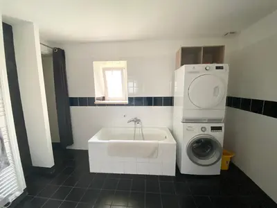 a bathroom with a sink and a washing machine at Gîte Du Bourrelier in Boutenac