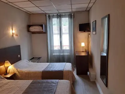 a hotel room with two beds and a window at Logis Hotels - Hôtel Le Boulevard in Mazamet
