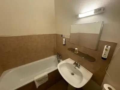 a bathroom with a sink and a tub and a mirror at Logis Hotels - Hôtel Le Boulevard in Mazamet