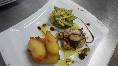 a plate of food with shrimp and vegetables on a table at Logis Hotels - Hôtel Le Boulevard in Mazamet