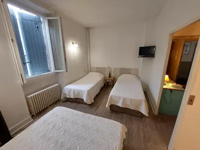 a small room with two beds and a window at Logis Hotels - Hôtel Le Boulevard in Mazamet