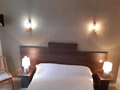 a bedroom with a bed and two lights on the wall at Logis Hotels - Hôtel Le Boulevard in Mazamet