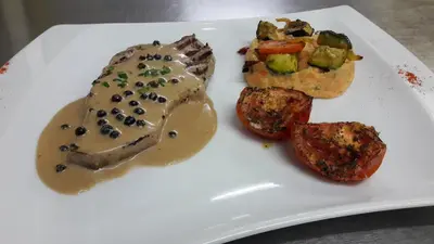 a white plate of food with meat and potatoes at Logis Hotels - Hôtel Le Boulevard in Mazamet