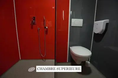 a bathroom with a red shower stall with a toilet at Hôtel La Rocade in Pamiers