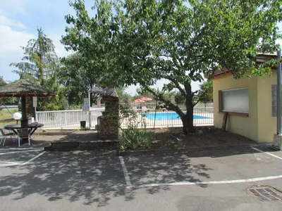 a building with a tree and a swimming pool at Hôtel La Rocade in Pamiers
