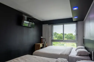 a hotel room with two beds and a window at Hôtel La Rocade in Pamiers