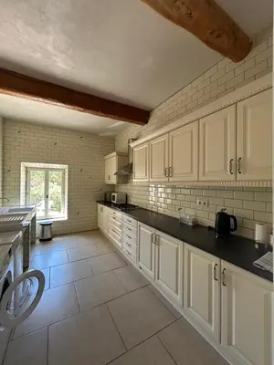 a kitchen with white cabinets and a tile floor at Domaine Les Salices in Azille