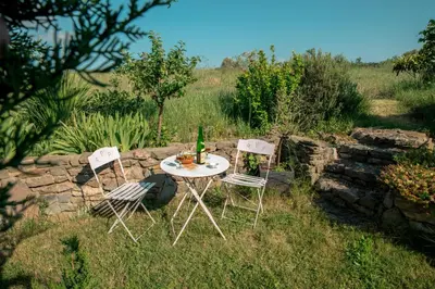 a table with two chairs and a bottle of wine at Relais de l'Alaric in Moux