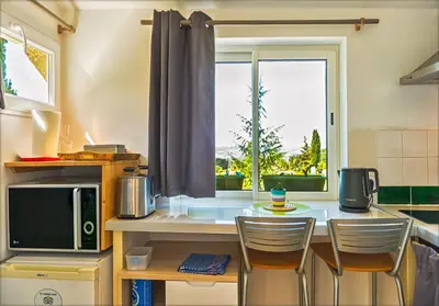 a kitchen with a counter with chairs and a window at Ecuries Sainte Croix in Carcassonne