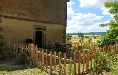 a fence in front of a house with a table at La Bonne Planque - Maison éclusière de la Domergue Canal du Midi in Mas-Saintes-Puelles