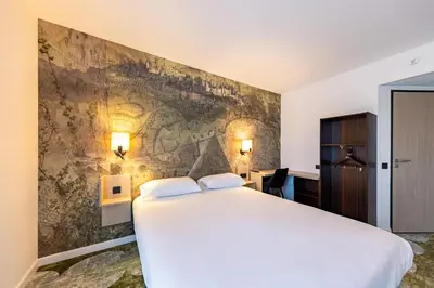 a bedroom with a large bed and a stone wall at Hôtel Pont Rouge , Carcassonne in Carcassonne