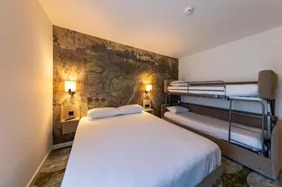 a bedroom with two bunk beds and a stone wall at Hôtel Pont Rouge , Carcassonne in Carcassonne