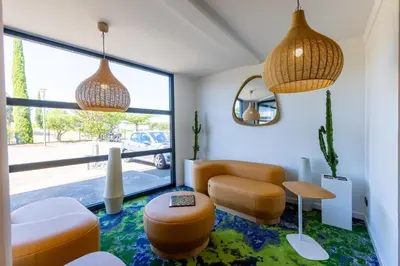 a living room with orange chairs and a table at Hôtel Pont Rouge , Carcassonne in Carcassonne
