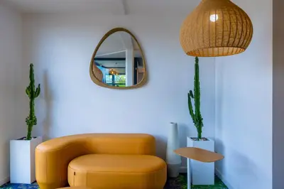 a living room with a yellow chair and a mirror at Hôtel Pont Rouge , Carcassonne in Carcassonne