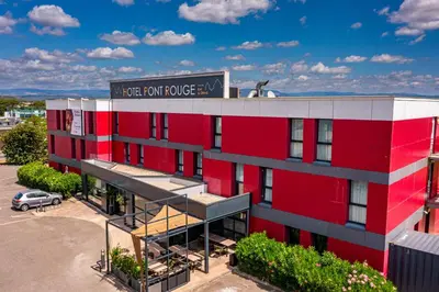 an image of a red building with a parking lot at Hôtel Pont Rouge , Carcassonne in Carcassonne