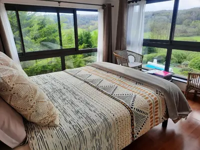 a bedroom with a bed and a large window at Belloréade Maison d'hôtes in Belloc