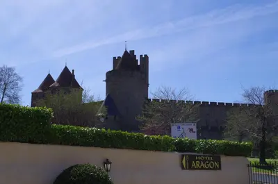 a swimming pool with lounge chairs and a house at Hôtel l'Aragon in Carcassonne