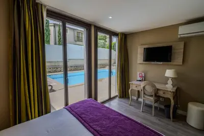 a bedroom with a bed and a desk and a tv at Hôtel l'Aragon in Carcassonne
