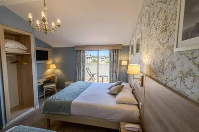 a bedroom with a bed and a desk and a window at Hôtel l'Aragon in Carcassonne