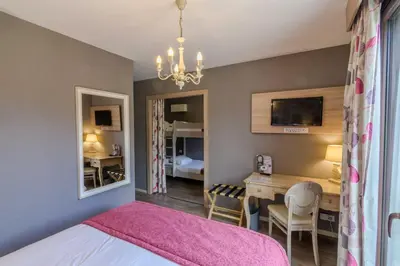 a bedroom with a pink bed and a dining room at Hôtel l'Aragon in Carcassonne