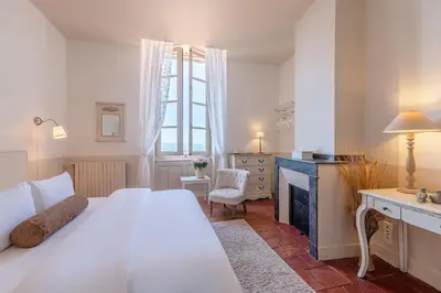 a bedroom with a large white bed and a desk at Cap de Castel in Puylaurens