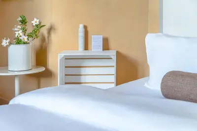 a white bed with a dresser and a table with a plant at Cap de Castel in Puylaurens