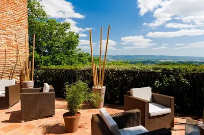 a patio with wicker chairs and potted plants at Cap de Castel in Puylaurens