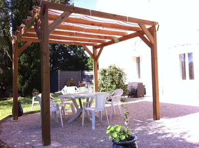 a wooden pergola with a table and chairs at Maison Majorelle in Moussoulens