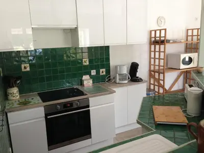 a kitchen with white cabinets and green tile at Maison Majorelle in Moussoulens