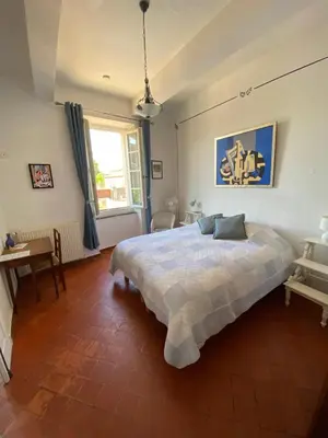 a bedroom with a bed and a table and a window at La Marelle chambre d hôtes à 500m du Canal du Midi in La Redorte