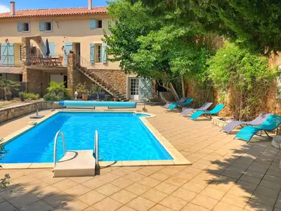 a swimming pool with blue chairs and a house at Pradines in Saint-André-de-Roquelongue