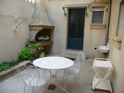 a patio with a table and chairs in front of a door at Havre de Paix Centre ville Narbonne, T3 confortable, près de l'ARENA et du GRAND BUFFET in Narbonne