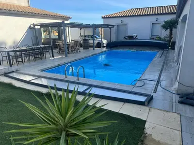 a swimming pool in a backyard with a table and chairs at Nid douillet in Villemoustaussou
