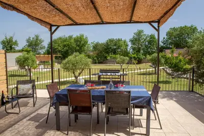 a patio with a table and chairs under a roof at Gîtes Chantelauze in Narbonne