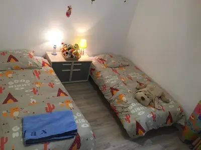 a bedroom with two beds and a desk with a night stand at Gîte de Marie in Burlats