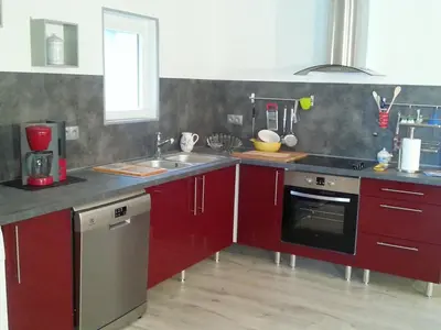 a kitchen with red cabinets and a sink at Gîte de Marie in Burlats