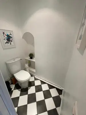 a bathroom with a toilet and a checkered floor at la maison des chapeliers in Carcassonne
