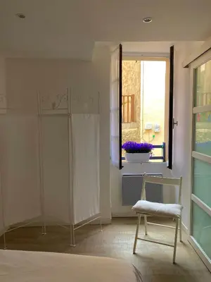 a bedroom with a bed and a chair and a window at La petite maison bleue in Gruissan