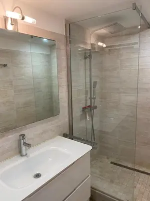 a bathroom with a sink and a glass shower at La petite maison bleue in Gruissan