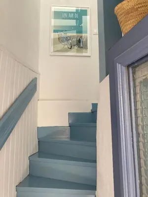 a staircase with blue stairs with a picture on the wall at La petite maison bleue in Gruissan