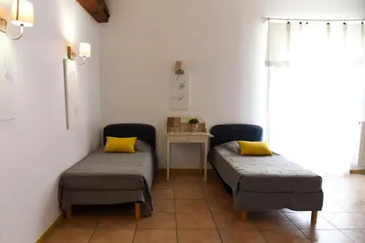 two beds in a room with a table and yellow pillows at La Bergerie de l'etang in Montels