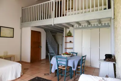 a room with a table and chairs and a staircase at La Bergerie de l'etang in Montels