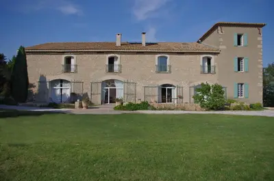 a large brick house with a green lawn in front of it at La Bergerie de l'etang in Montels