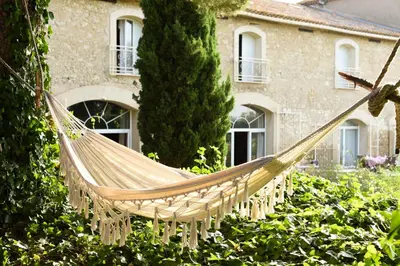 a hammock in a garden in front of a house at La Bergerie de l'etang in Montels
